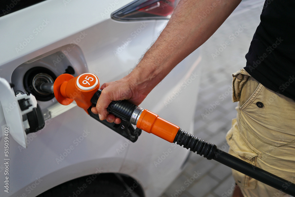 man's hand holds a filling pistol inserted into the gas tank hole of a car at a gas station. Close-up of a hand and a refueling gun. The concept of the high cost of fuel, inside out empty pockets man's hand holds a filling pistol inserted into the gas tank hole of a car at a gas station. Close-up of a hand and a refueling gun. The concept of the high cost of fuel, inside out empty pockets