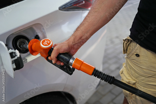 man's hand holds a filling pistol inserted into the gas tank hole of a car at a gas station. Close-up of a hand and a refueling gun. The concept of the high cost of fuel, inside out empty pockets