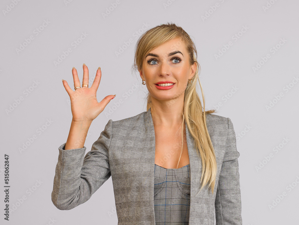 business woman in a gray suit joyfully waves her open palm, half-length portrait on a white background business woman in a gray suit joyfully waves her open palm, half-length portrait on a white background