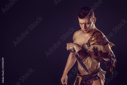 Portrait of handsome muscular gladiator with sword. Isolated. Studio shot. 