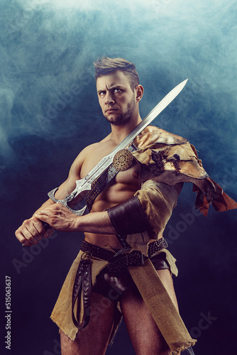 Portrait of handsome muscular gladiator with sword. Isolated. Studio shot. 