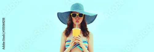 Summer portrait of young woman model drinking fresh juice wearing straw hat on the beach on sea background