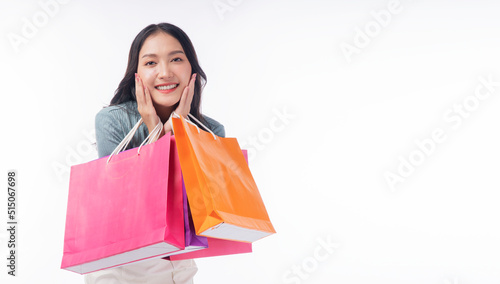 Enjoyment excited asian woman carry shopping bags standing on white background. Trendy happy shopper consumer carefree young girl holding shopping paper bags with copy space over isolated background.