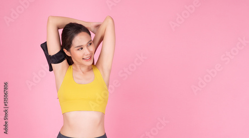Cheerful slim asian women wear yellow sportswear stretching arms looking copy space on pink background. Activity young girl relax after exercise stretch body over isolated. Health care workout concept