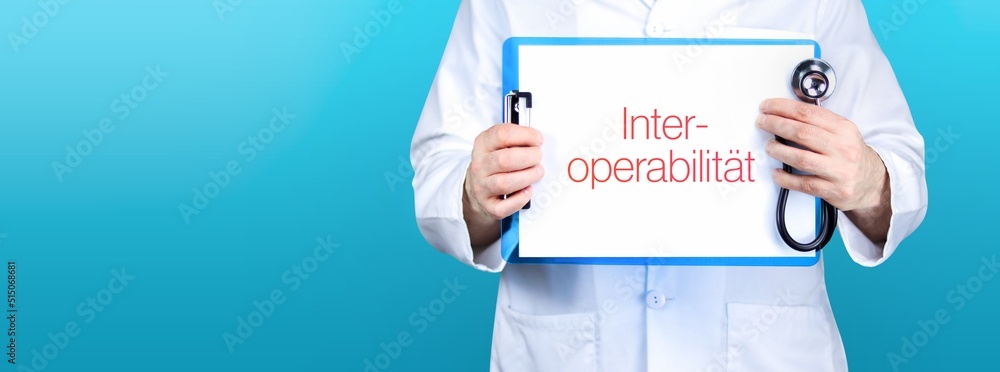 Interoperabilität. Arzt hält blaues Schild mit Papier. Wort steht auf Dokument. Stethoskop in der Hand. Interoperabilität. Arzt hält blaues Schild mit Papier. Wort steht auf Dokument. Stethoskop in der Hand.