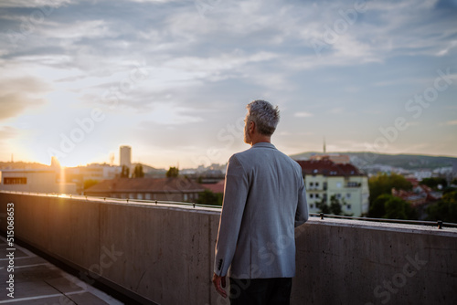 Rear view of mature businessman walking in city in evening, work life balance concept.