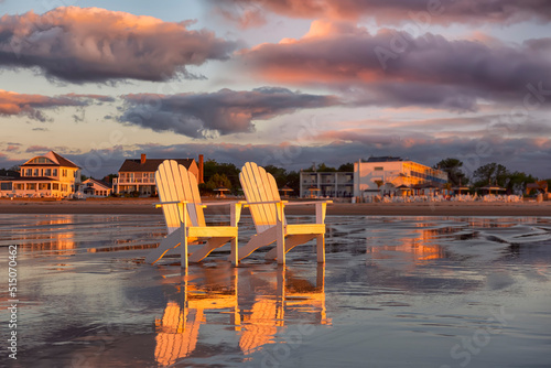 Two wooden traditional armchairs on a sandy beach at sunrise overlooking the coastline. Atlantic Ocean. USA. Maine. Old Orchard Beach. photo