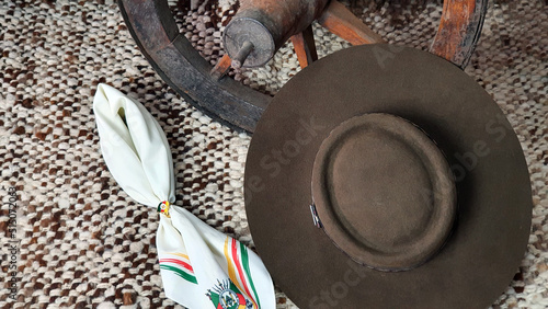 Hat, cart wheel and gaucho scarf with the symbol of the Flag of the State of Rio Grande do Sul - Brazil, on a rustic background. photo