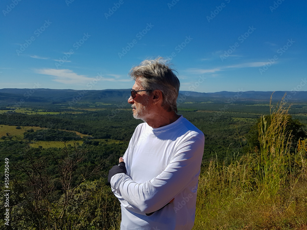 White haired man watching a green valley White haired man watching a green valley
