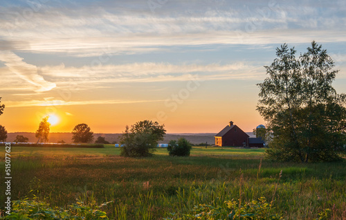 sunrise over the farm with barn and hay bales