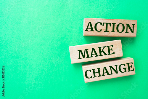 Action make change words on wooden blocks on green background.