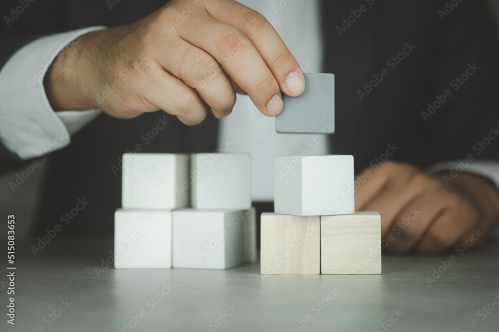 Hand putting wood cube on top of wood block stacking. Business growth to success. Hand putting wood cube on top of wood block stacking. Business growth to success.