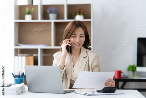 Asian businesswoman in formal suit in office happy and cheerful during using smartphone and working.