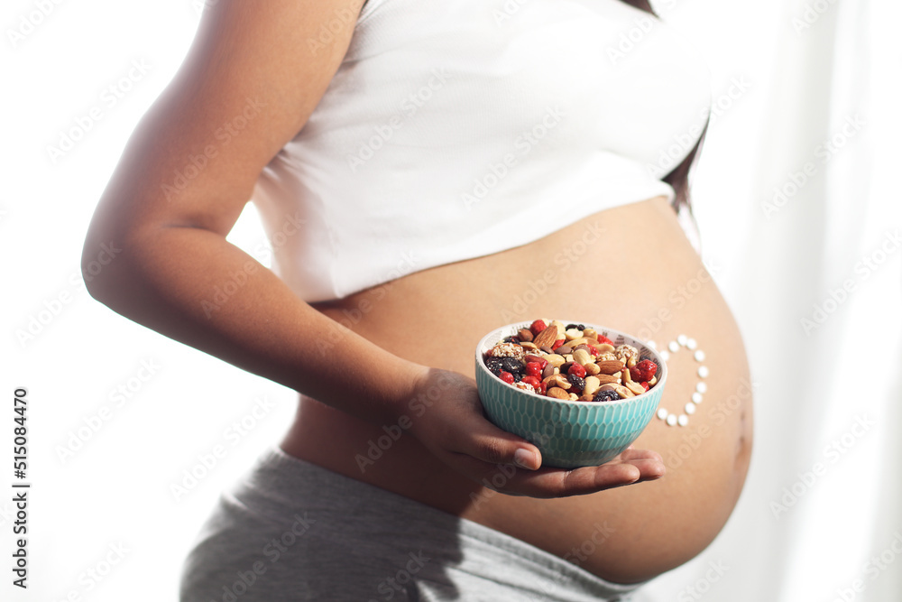 Pregnant woman belly holding dry fruits on hand Pregnant woman belly holding dry fruits on hand
