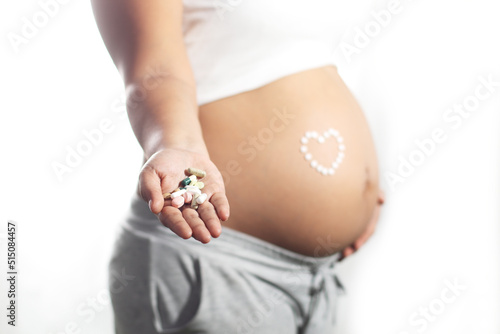 Pregnant woman latina with pills on right hand, white background