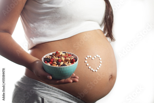 pregnant woman holding a bowl of dry fruit