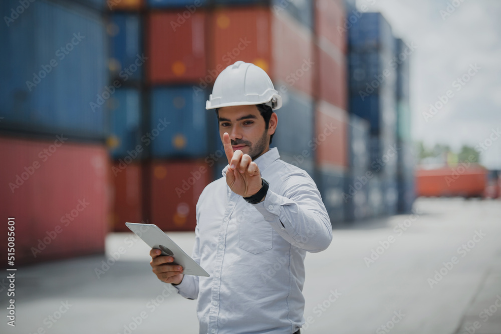 Engineer worker in causual suit standing in shipping container yard holding laptop with smile. Import and export product. Manufacturing transportation and global business concept Engineer worker in causual suit standing in shipping container yard holding laptop with smile. Import and export product. Manufacturing transportation and global business concept