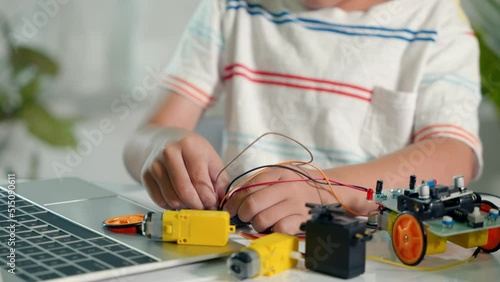 Asian kid boy plugging energy and signal cable to sensor chip with Arduino robot car, Little child remotely learn online with car toy, STEAM education AI technology course school learning lesson