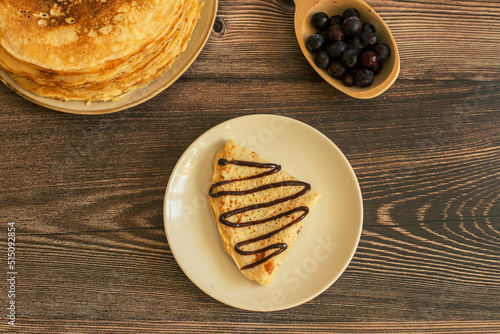 Delicious pancakes with chocolate sauce fresh blueberries on a rustic wooden table. Rustic brown table. 