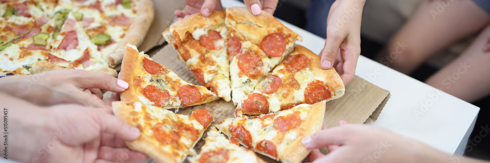 Hands of big company take piece of round shaped pizza Hands of big company take piece of round shaped pizza