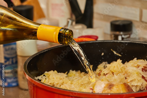 Pieces of smoked pork and sausage in saucepan are poured with white wine to make Alsatian sauerkraut