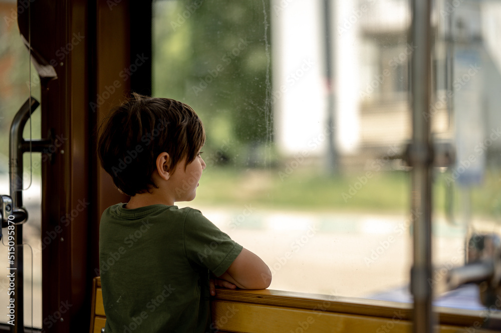 a boy rides a trama boy rides a tram, a child views the city through the window of public transport.