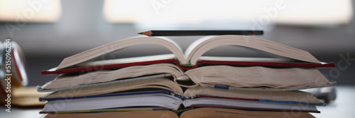 Stack of books lay on table, undone homework tasks or things to learn at home