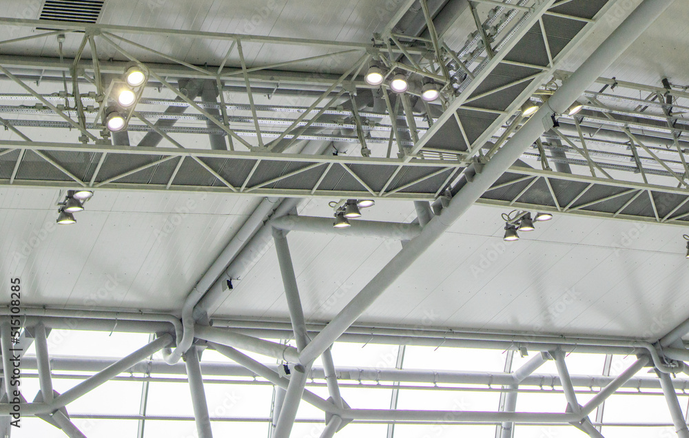 Ceiling with bright lighting in a modern warehouse, shopping center building, airport or other commercial real estate object. Directional LED lights on rails under the ceiling Ceiling with bright lighting in a modern warehouse, shopping center building, airport or other commercial real estate object. Directional LED lights on rails under the ceiling