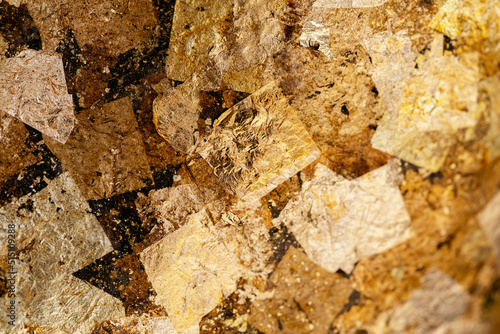 Closeup. Background image of small gold leaf that has been pasted to surface of several parts of Buddha statue until it is beautiful.