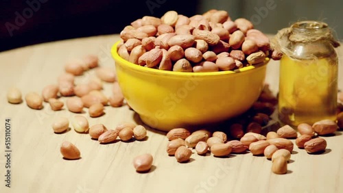 Whole peanut and peanut oil on table, eatable groundnut oil,peanuts in wooden bowl with canola oil,selective focus