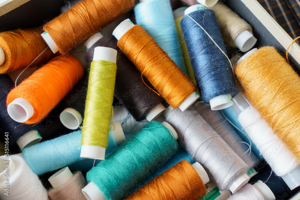 Background of many colorful spools of thread closeup. Sewing hobby concept. Pile of threads bobbins Background of many colorful spools of thread closeup. Sewing hobby concept. Pile of threads bobbins