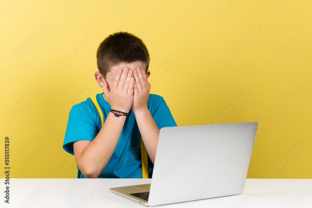 Teenager boy hands on face whatching inappropriate content for his age on laptop isolated on yellow background. Teenager boy hands on face whatching inappropriate content for his age on laptop isolated on yellow background.