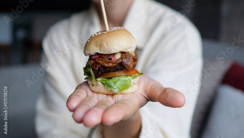 A mini hamburger in the palm of your hand with a delicious filling of vegetables and vegetarian meat to replace unhealthy fats. Tasty and healthy fast food. The concept of eating fast food in the usa.