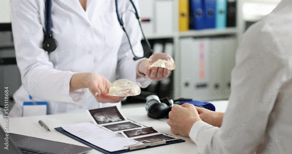 Female plastic surgeon shows silicone breast implant to patient Female plastic surgeon shows silicone breast implant to patient