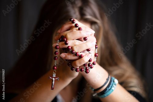 Christianity theme – prayer.  Christian woman with Bible praying with hands crossed keeping rosary. photo
