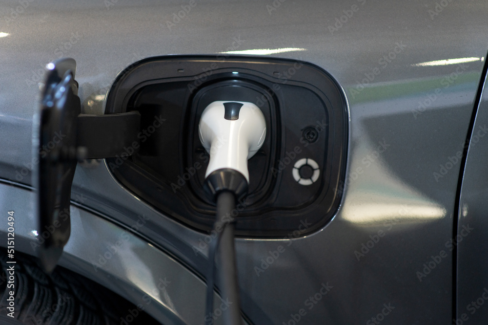 Closeup of power supply plugged into an modern electric car. Electric or EV car charging station.