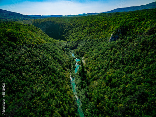 Fotografie Aerial view of deep green woods canyon with turquoise river in summer Croatia