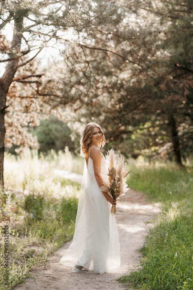 happy bride girl in a white light dress with a bouquet of dried flowers happy bride girl in a white light dress with a bouquet of dried flowers