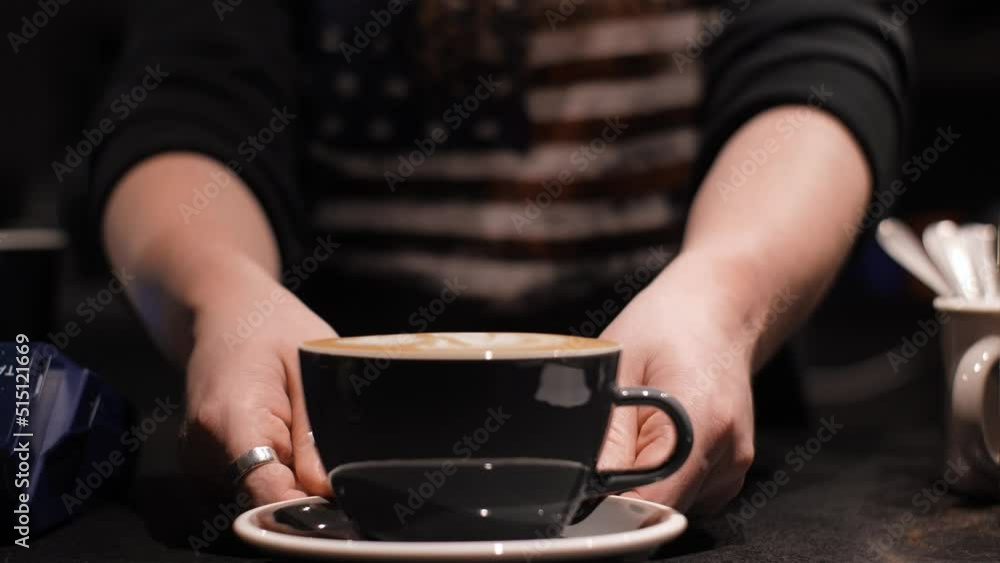 Barista with the US flag printed on their clothes serves delicious coffee. Male hands move cappuccino with foam, close up Barista with the US flag printed on their clothes serves delicious coffee. Male hands move cappuccino with foam, close up