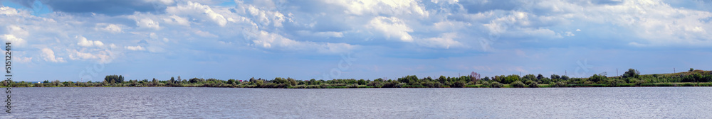 Panorama of the lake with a forest on the opposite shore under cloudy skies