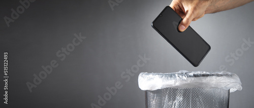 Fotografie Male hand throws smartphone into the trash.