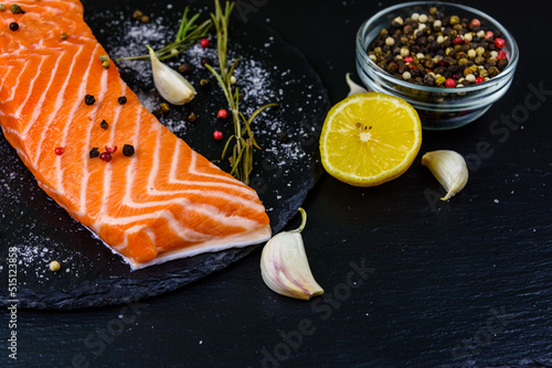 Raw fillet of salmon fish and spices on a slate board