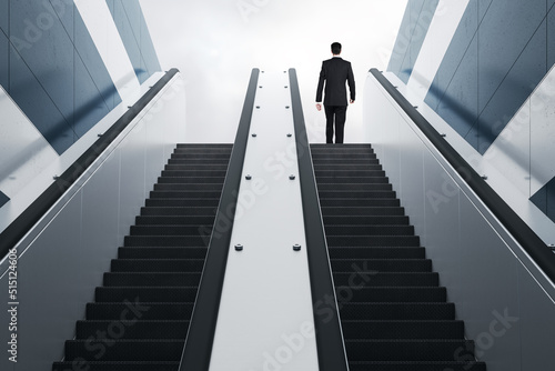 Back view of young man on top of escalator. Lift to success concept.
