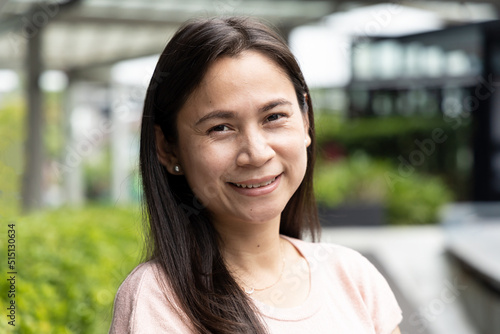 Fotografie Happy smiling middle aged asian woman in green city environment