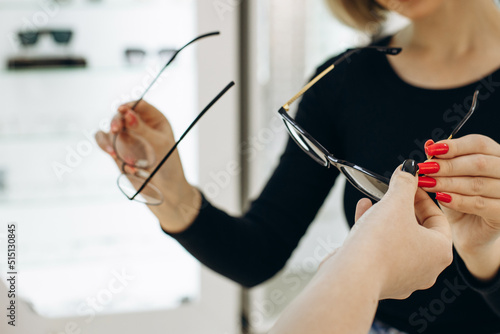 Woman choosing a pair of eyeglasses at optics store