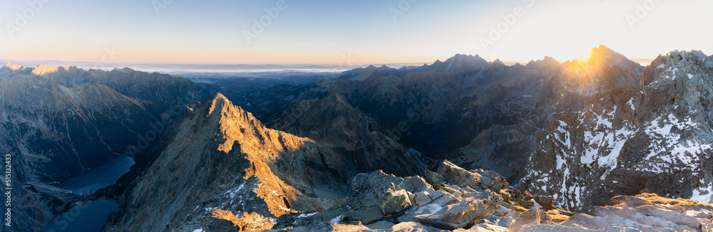 Panoramic view on alpine landscape with tarns and rocky mountain peaks during sunrise, Europe
