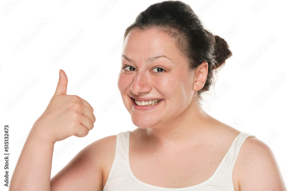Smiling chubby woman showing thumbs up on a white studio background Smiling chubby woman showing thumbs up on a white studio background