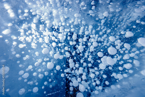 Gas methane bubbles frozen in winter ice of lake Baikal, abstract background