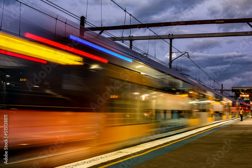 Fast train with motion blur, lone man stands on platform