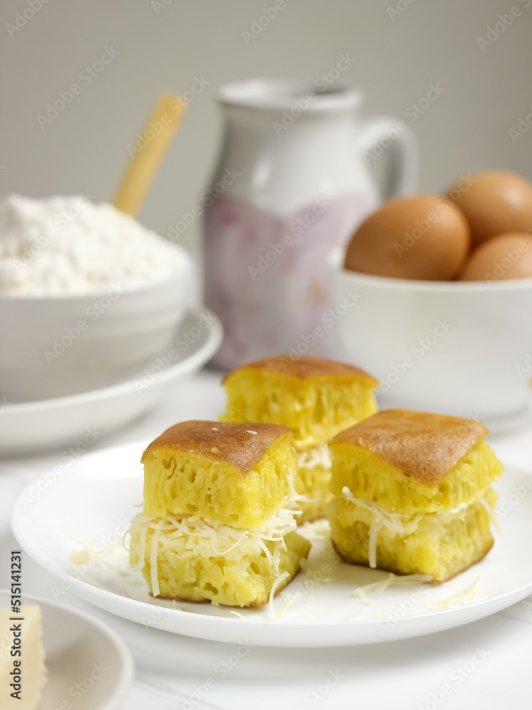 Martabak Keju, Indonesian Traditional Street Food Named Martabak Manis (Sweet Martabak) with Grated Cheese on WhiteTable. Selective focus Martabak Keju, Indonesian Traditional Street Food Named Martabak Manis (Sweet Martabak) with Grated Cheese on WhiteTable. Selective focus